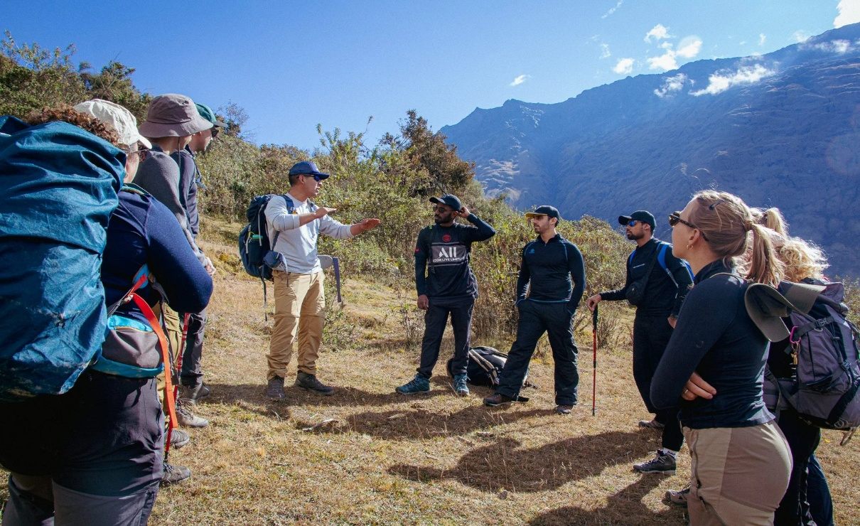 Grupo de viajantes escuta as orientações do guia durante um trekking