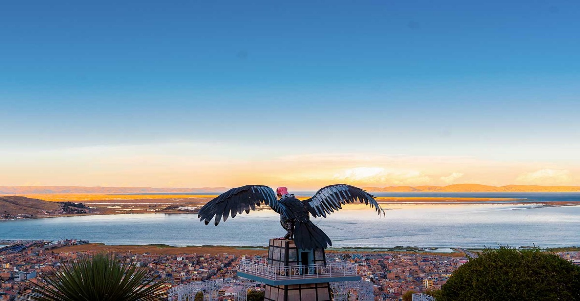 Vista de Puno e do lago Titicaca atrás de uma escultura de condor
