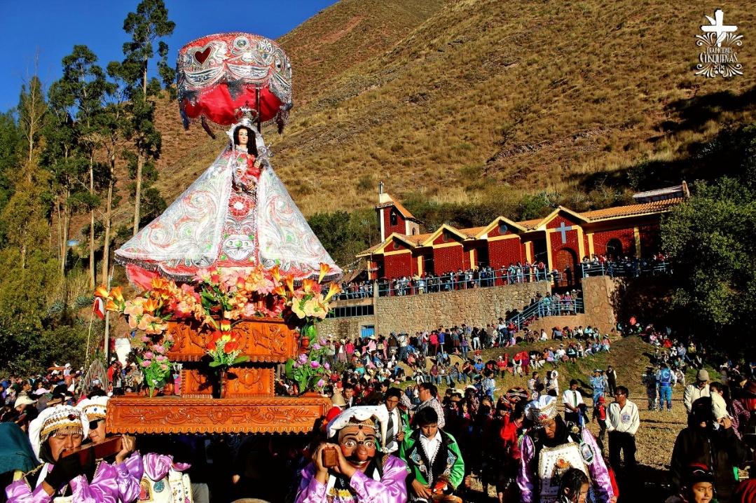 Procissão religiosa com flores e participantes em um povoado andino